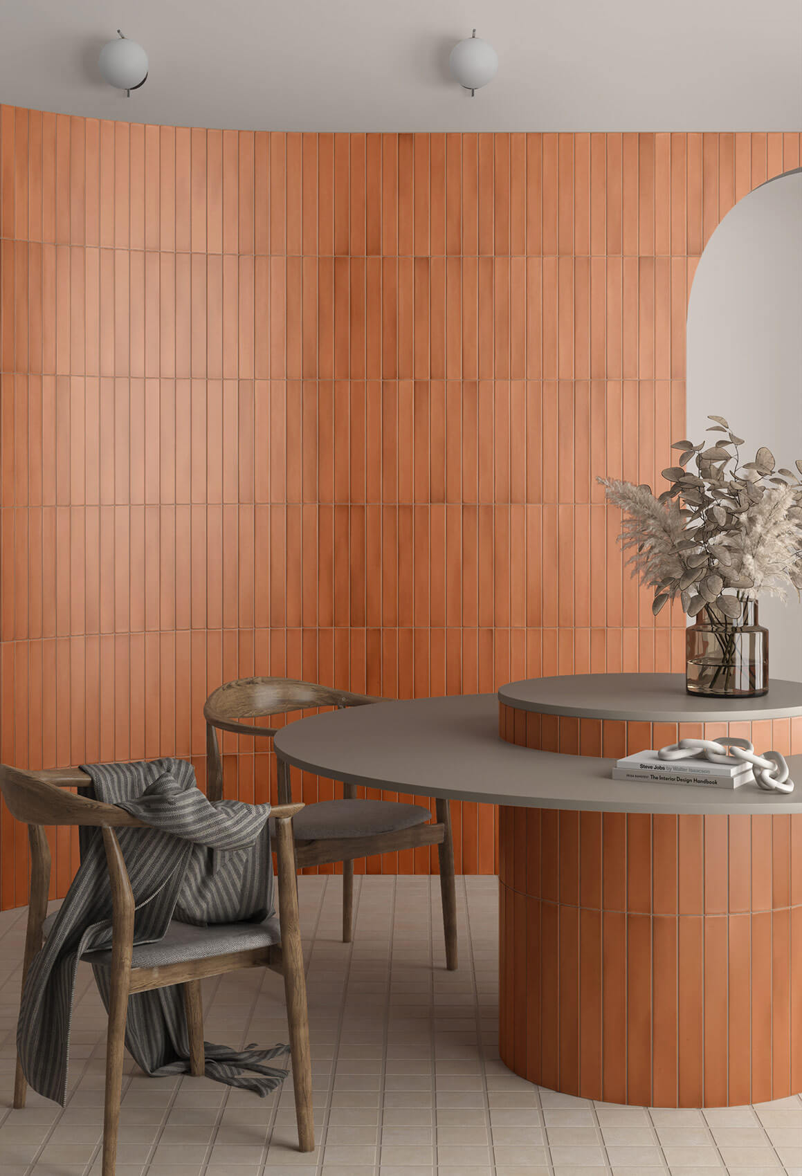 Curved wall with orange subway tiles on it, two wooden dining chairs around a round tiled table with timber top.