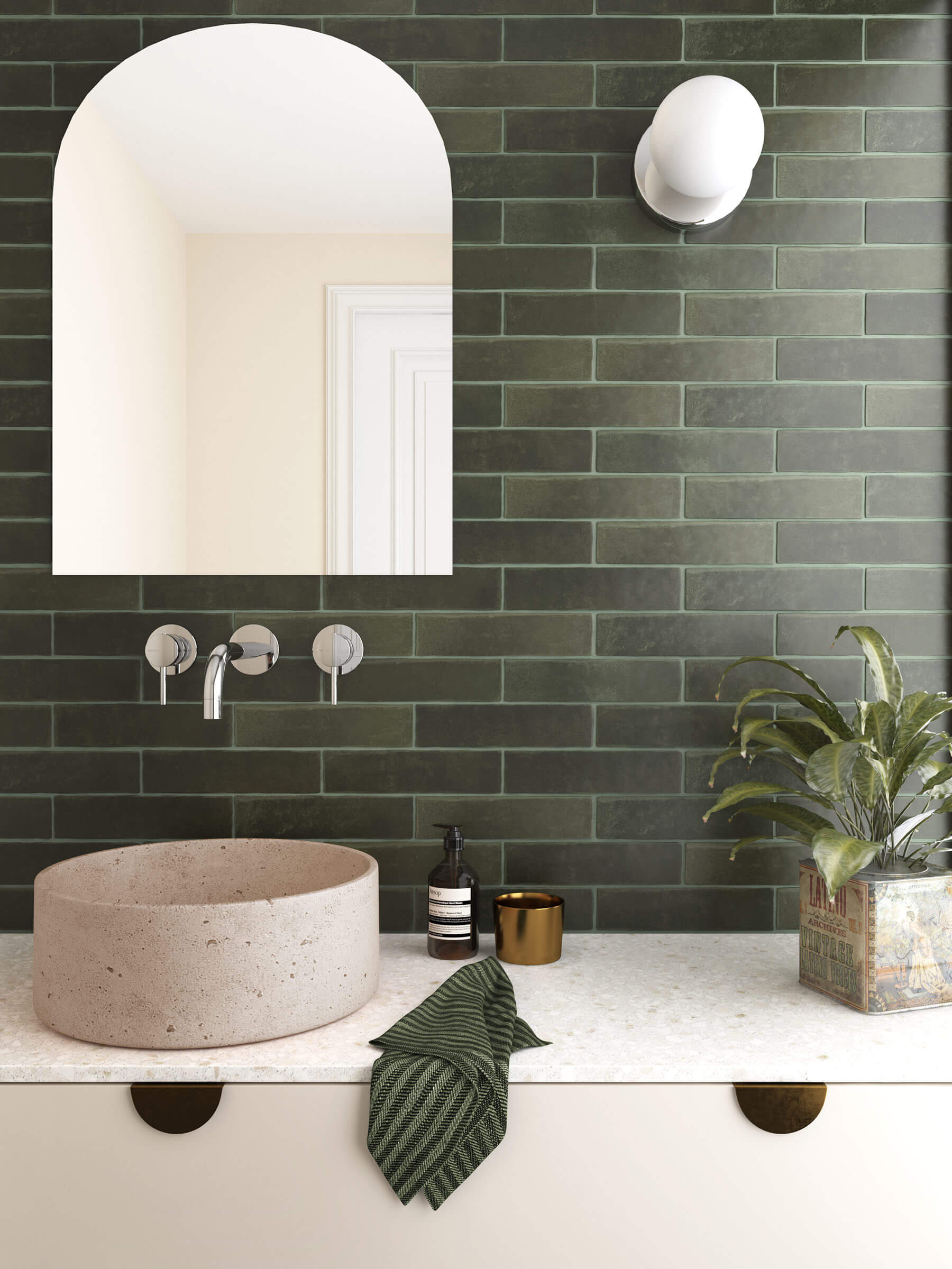 Close up of bathroom showing stone benchtop and stone basin and feature wall of deep green subway tiles laid horizontally.