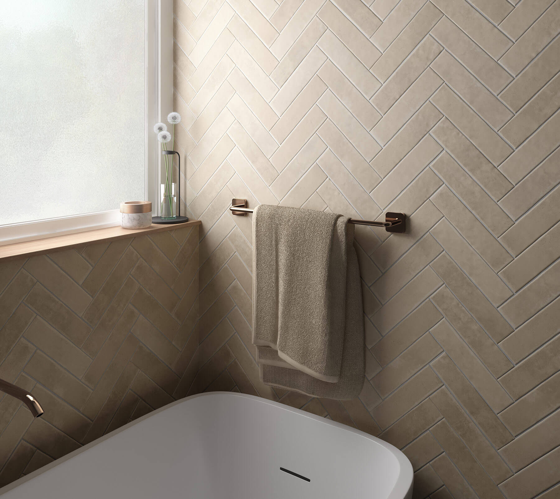 Feature wall in bathroom of sand colour subway tiles laid in herringbone pattern. White bath.
