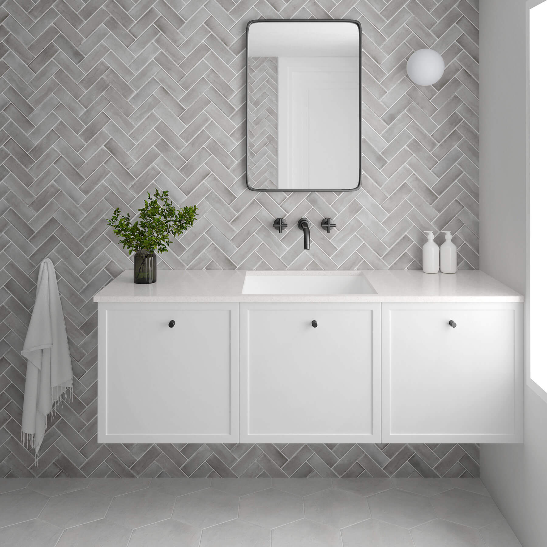 Feature wall in a bathroom of grey subway tiles laid in herringbone pattern. Which vanity and walls. Light grey floor tiles in honeycomb shape.