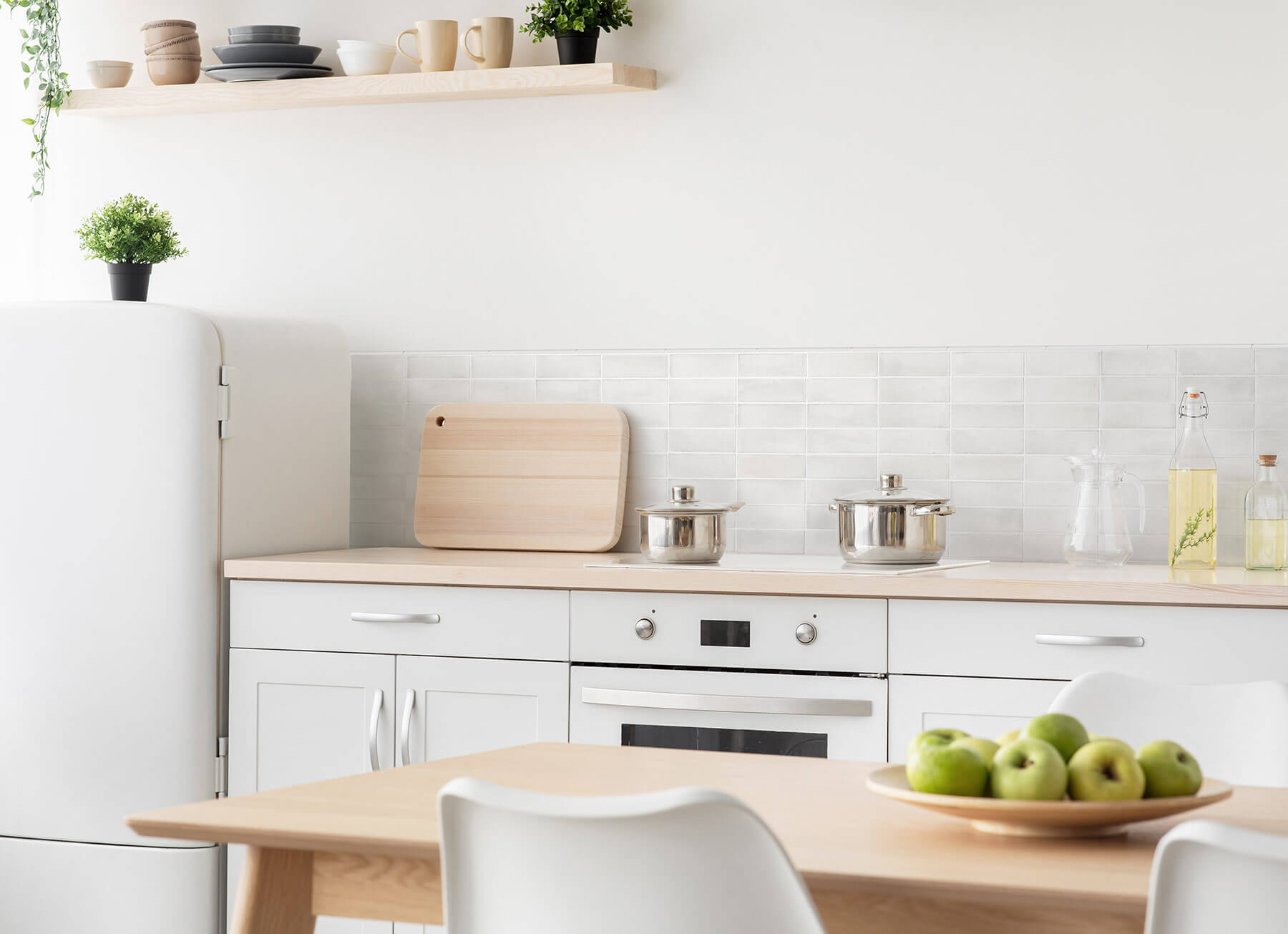 Close up of kitchen with white cabinets and walls, timber benchtops, and light grey subway tile splashback.
