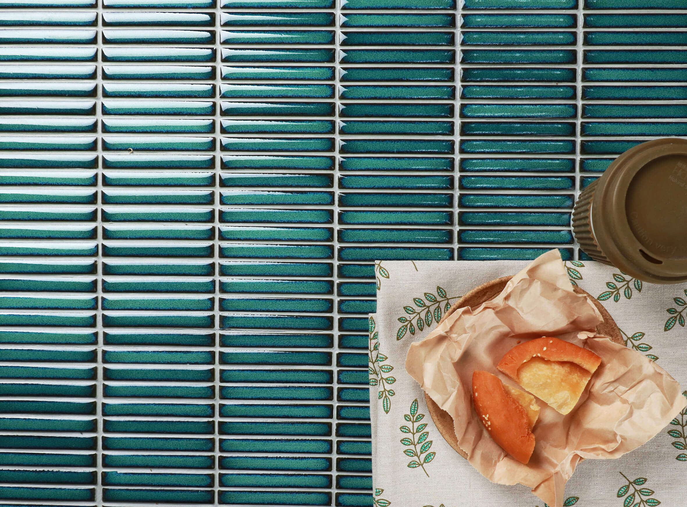 Close up of teal colour glossy subway tiles laid horizontally.