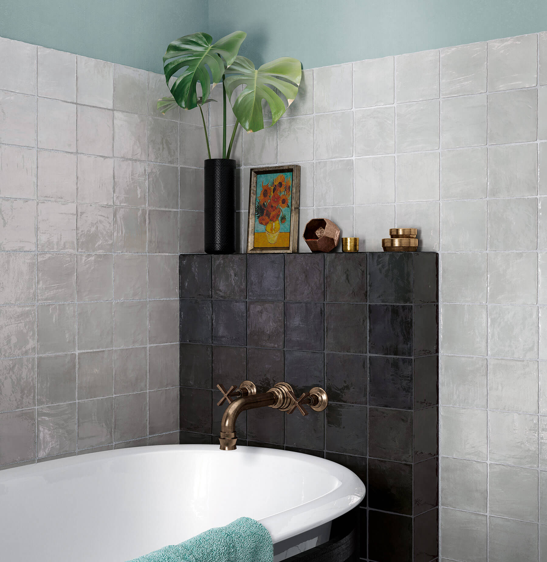 Close up of a corner of bathroom with black square tiles, bronze tapware and grey square tiles on the walls.