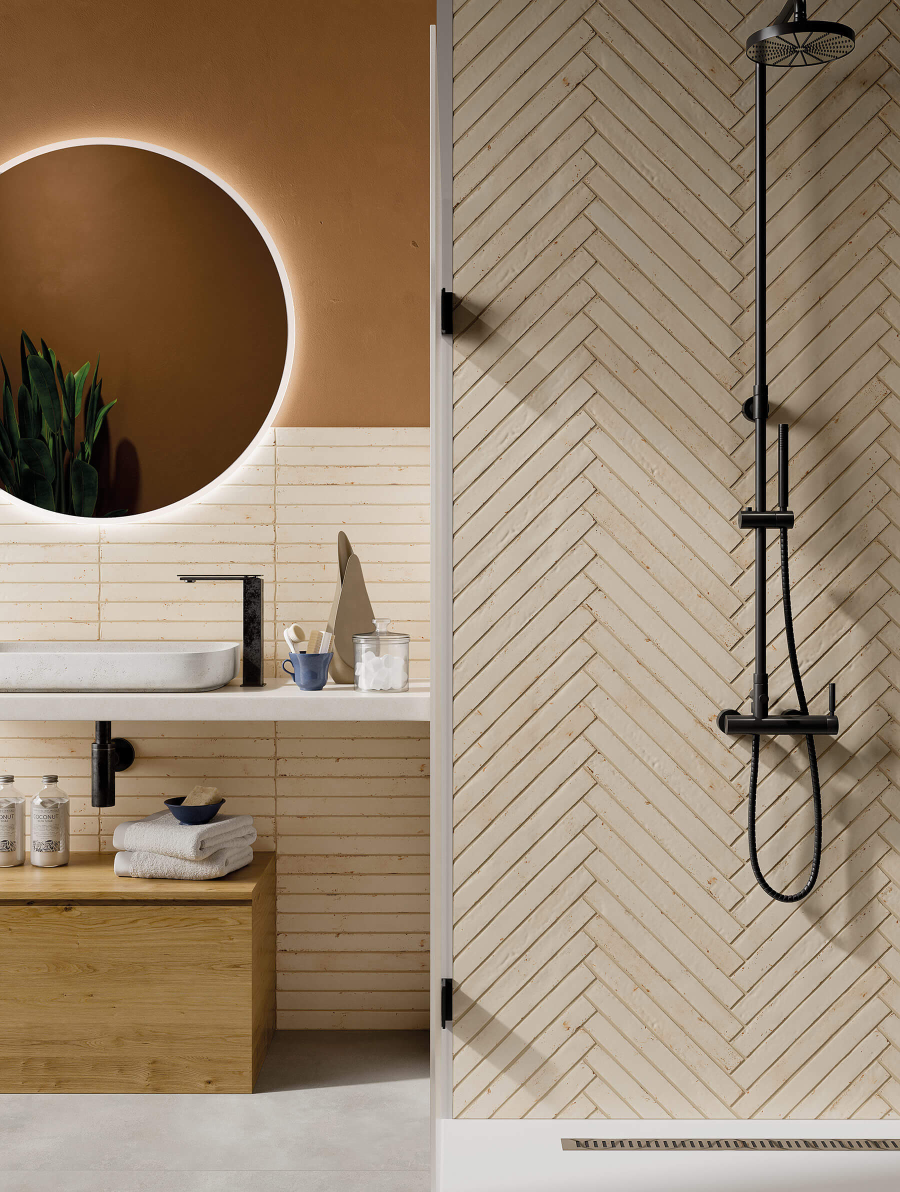 Bathroom feature wall of long thin cream subway tiles that look like stone, laid in herringbone pattern.