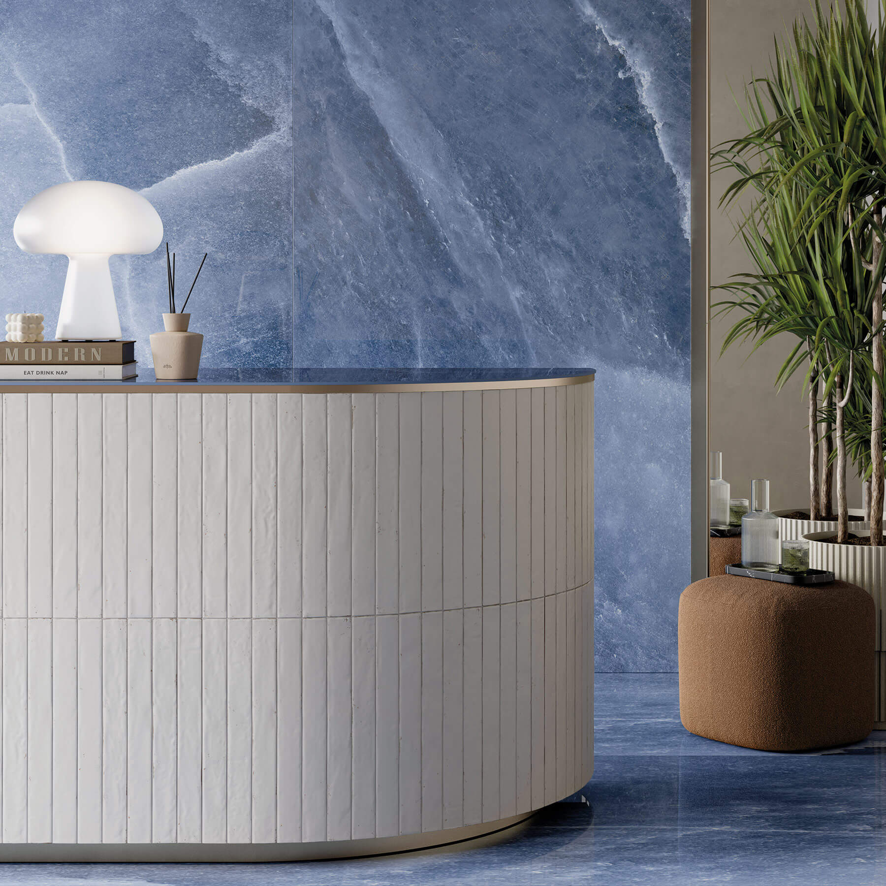A curved reception counter in a boutique with long cream subway tiles laid vertically, and large, square ocean blue tiles on the floor and wall.
