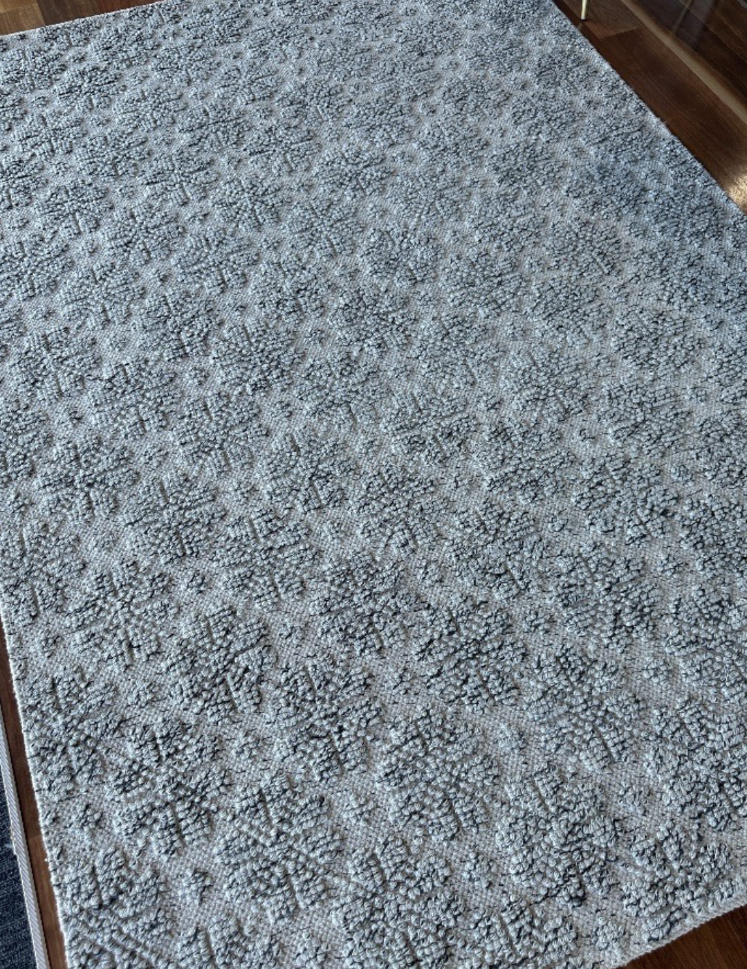 Modern rug with floral pattern woven in to it, the rug is a light grey colour.