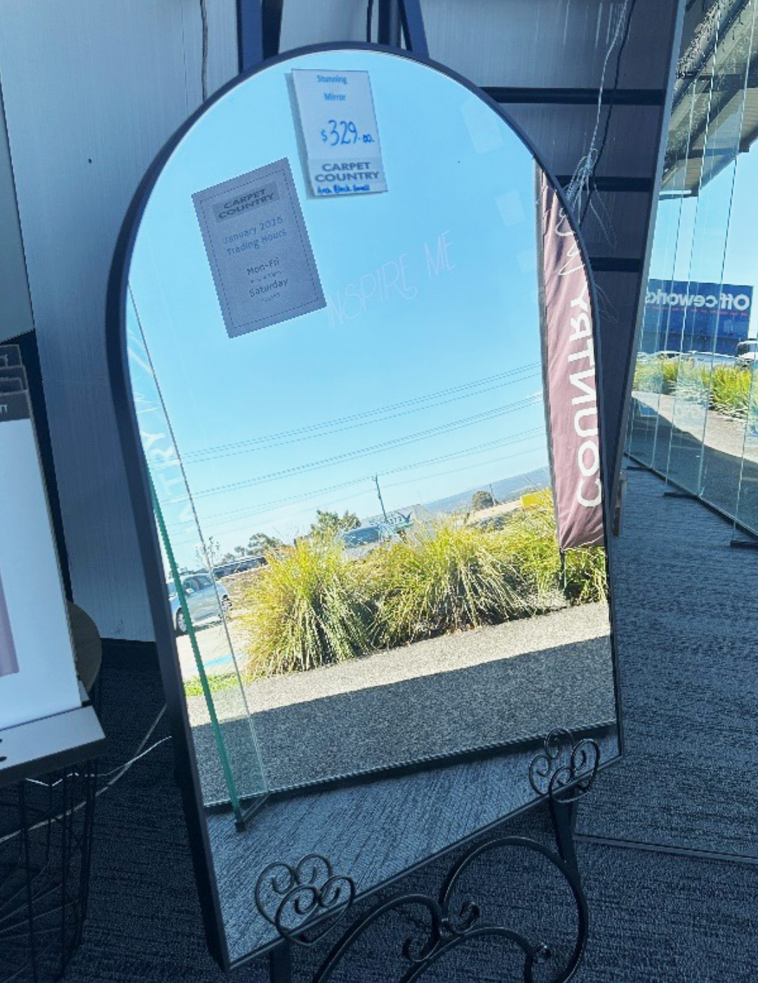 Small mirror with rounded top leaning against a wall in a store.