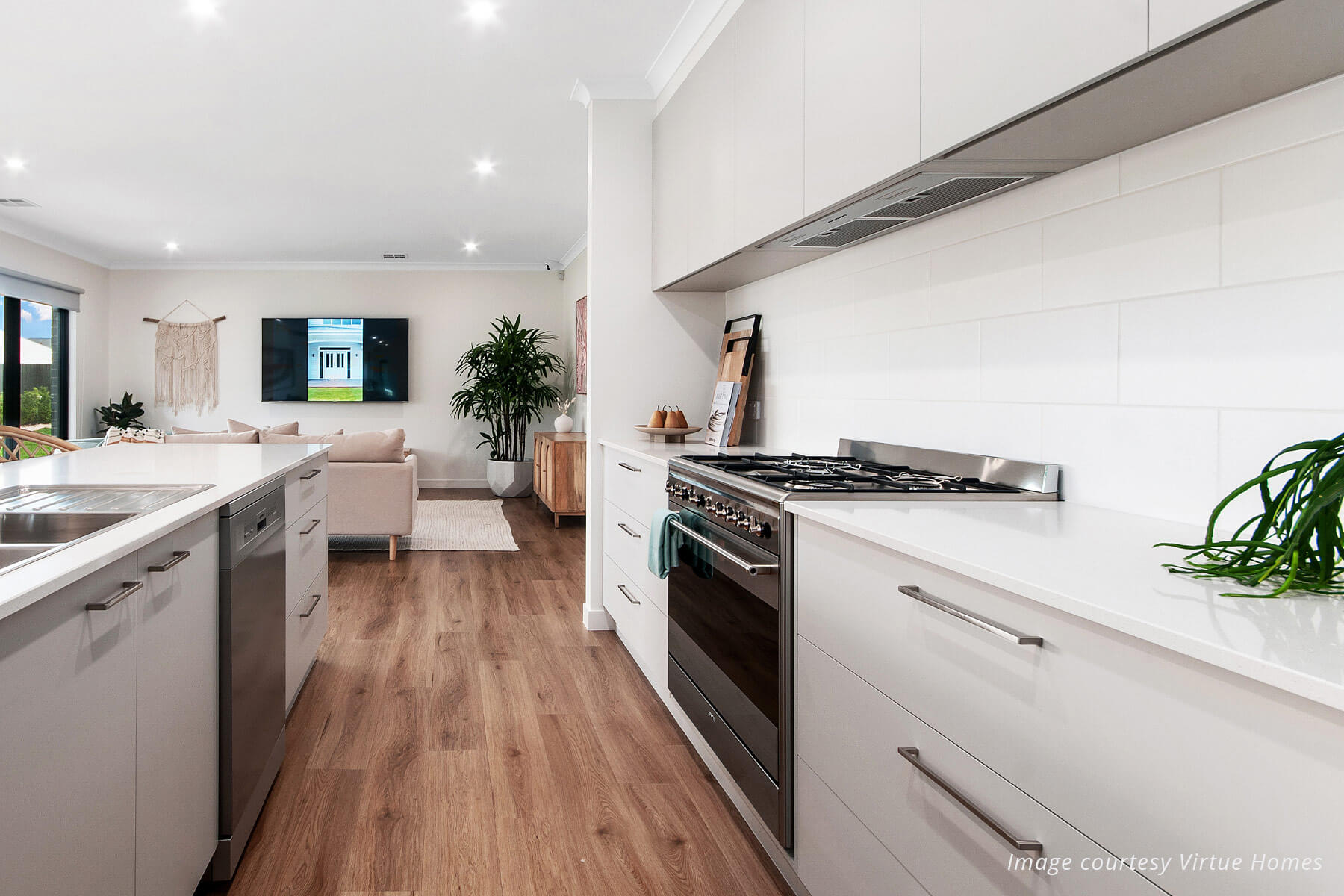 Modern white kitchen with living room couch and tv in the background