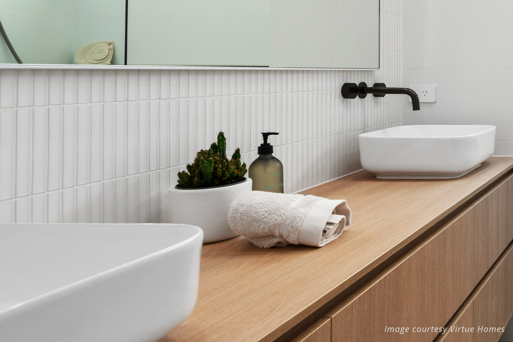 Close up of bathroom vanity showing quality timer vanity, white subway tiles, two white sinks and black tapware.