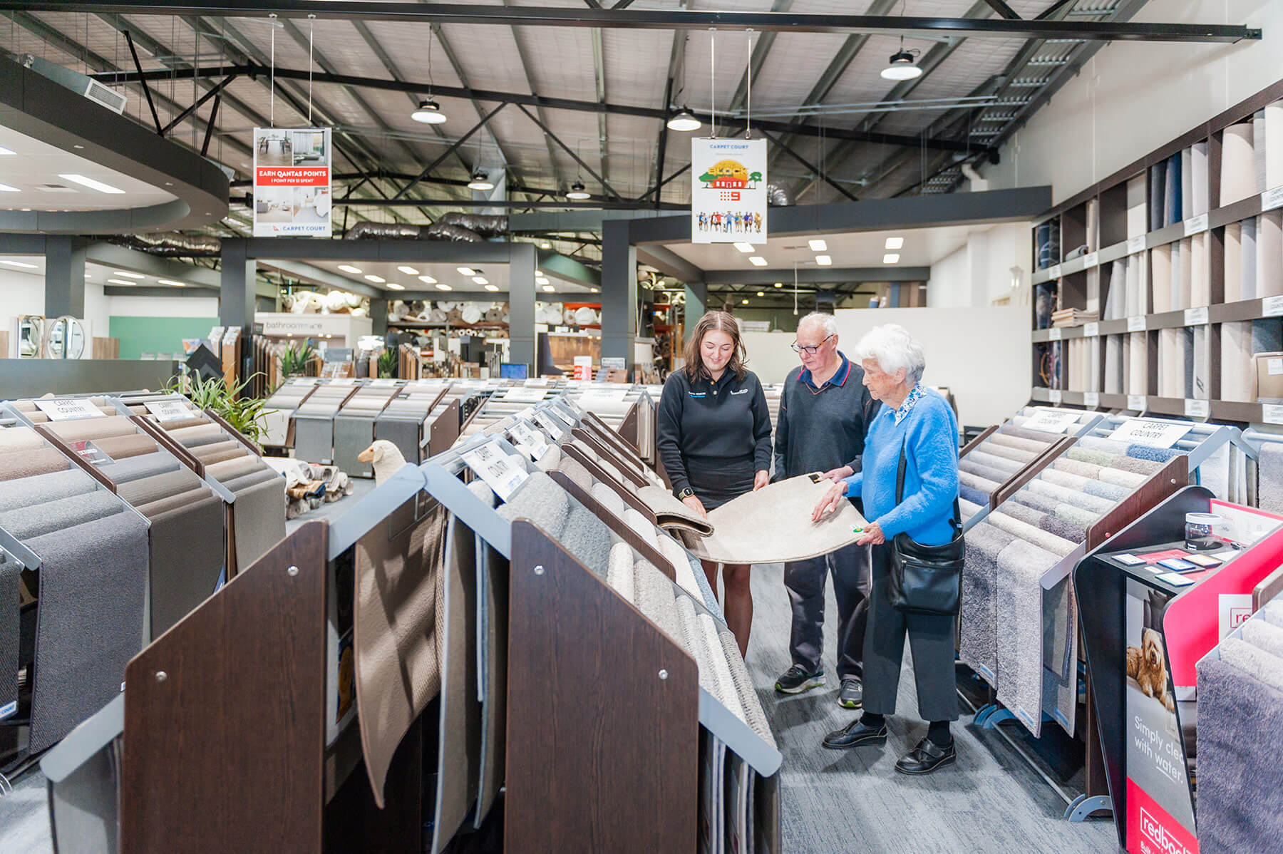 Laura Truscott showing customers samples of carpet in showroom.