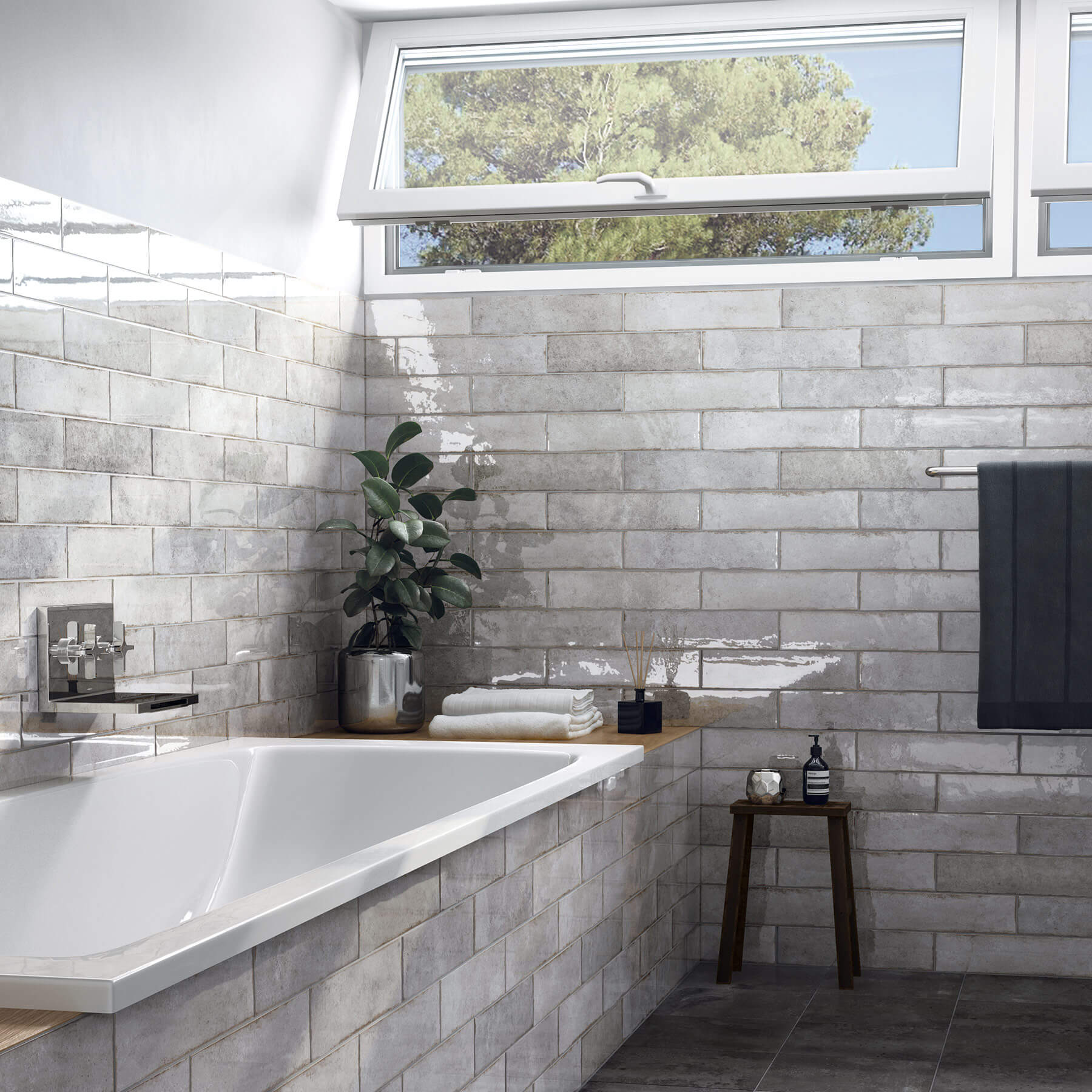 Close up of bathroom with white tub and feature grey subway tiles, tiles are laid like bricks and glossy.
